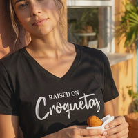 Video of a woman outside a Cuban ventanita bakery window holding a croqueta, wearing a black Raised on Croquetas women's v-neck t-shirt – Cuban American graphic tee, Miami gift by Martha of Miami