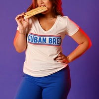 an image of martha of miami eating cuban toast and wearing a white v-neck t-shirt that says cuban bred in blue