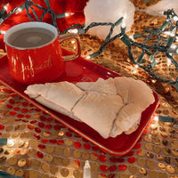 an image of a red coffee mug and cuban bread on top of a red dish plate that says dear santa, I'm sure Mrs. Claus tiene comida en la cada but just in case