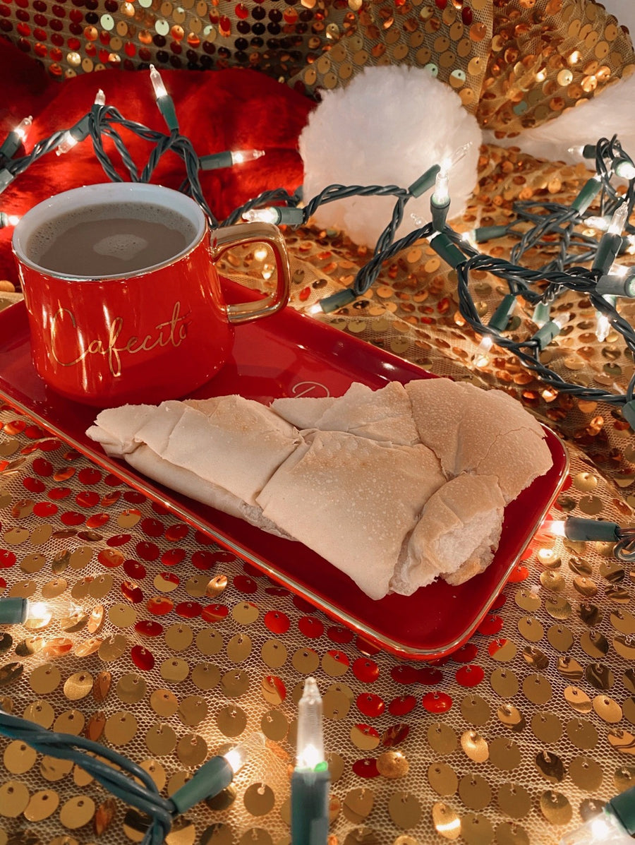 an image of a red coffee mug and cuban bread on top of a red dish plate that says dear santa, I'm sure Mrs. Claus tiene comida en la cada but just in case